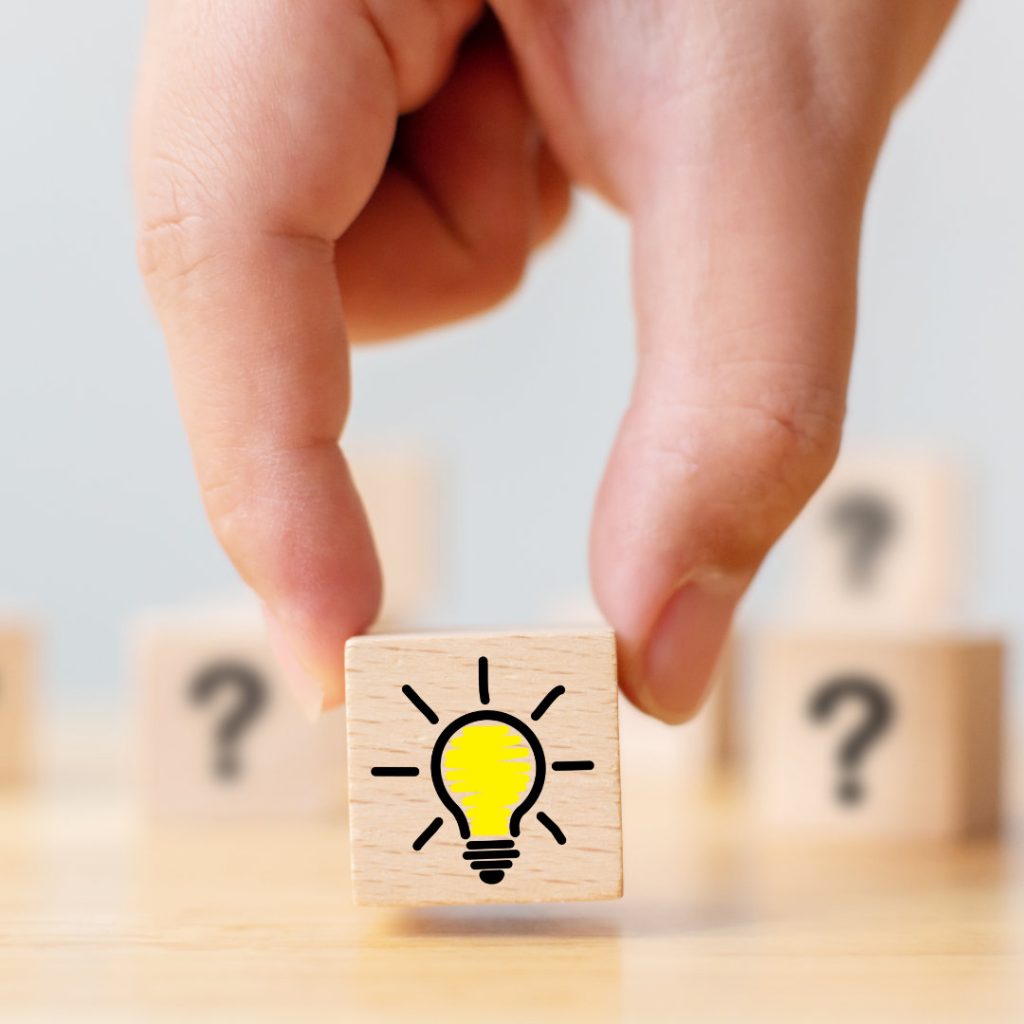 Concept creative idea and innovation. Hand picked wooden cube block with question mark symbol and light bulb icon